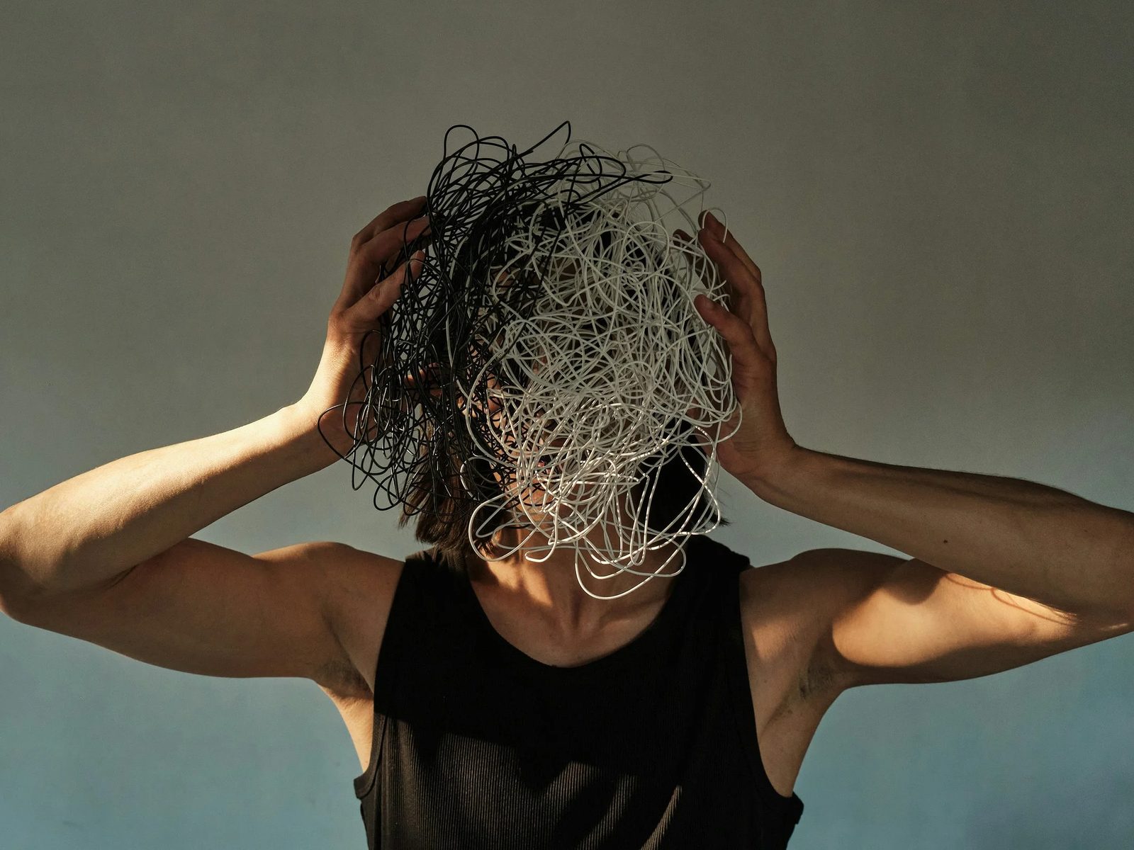 A person holding their head with a tangle of black and white scribbles over their face