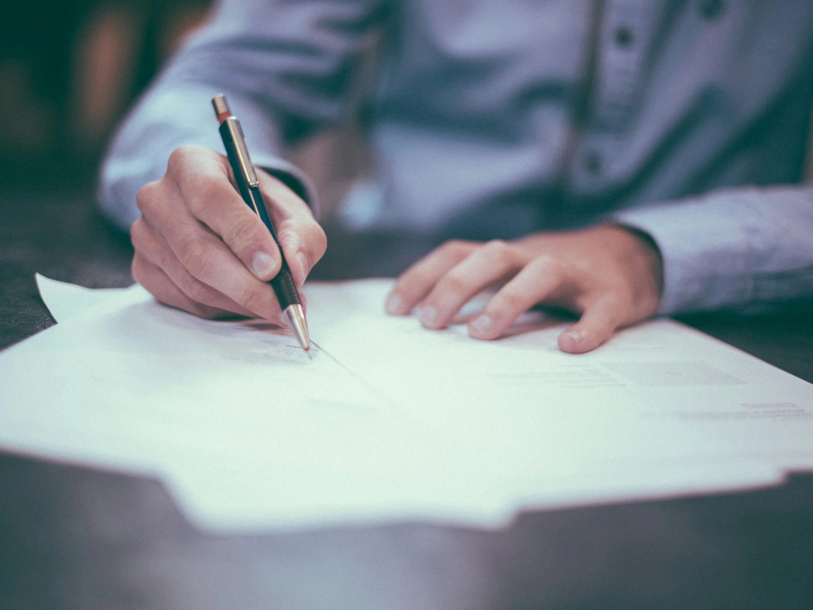 A hand writing with a pen on a sheet of paper