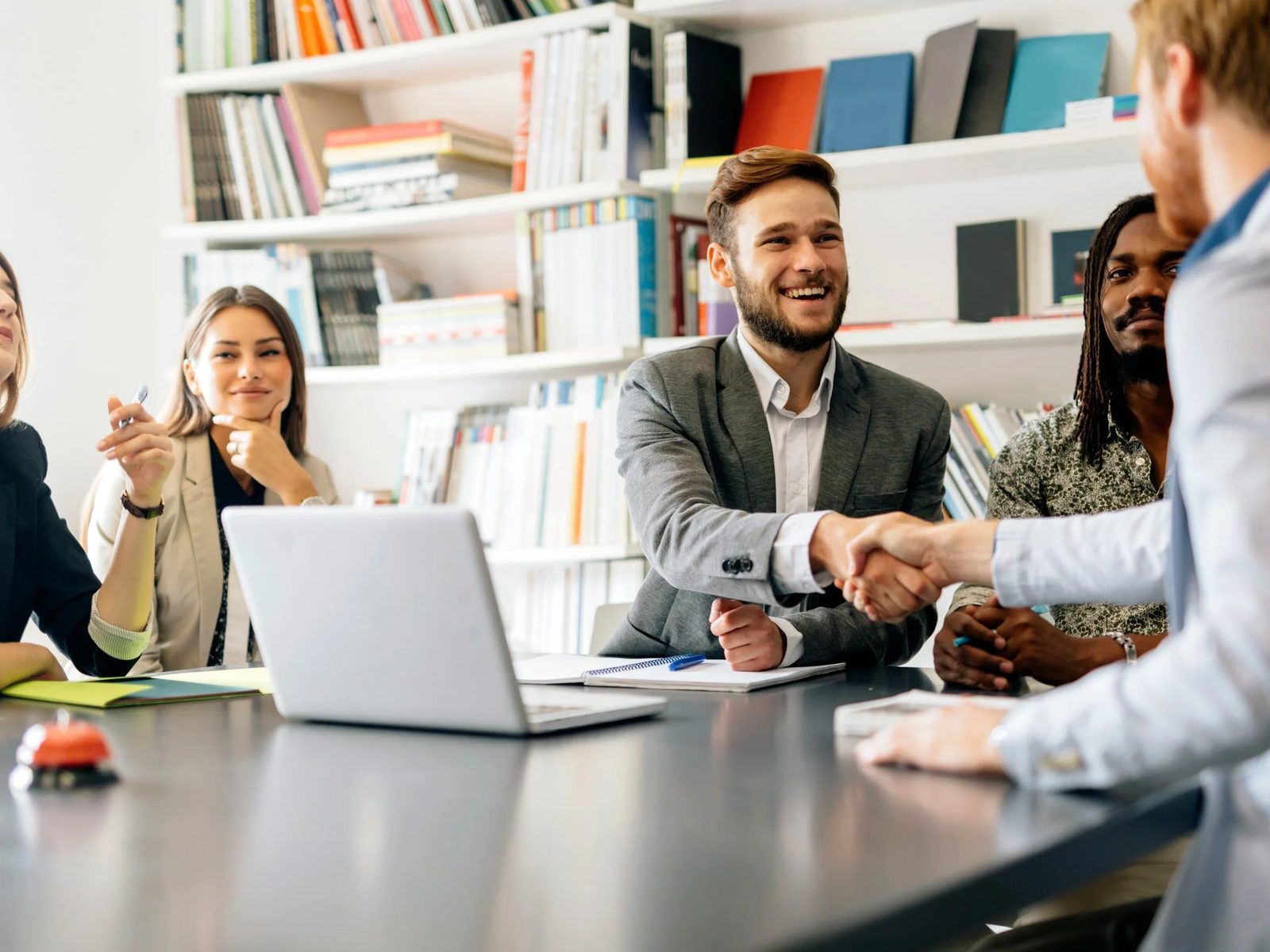 A team around a conference table, two people shaking hands
