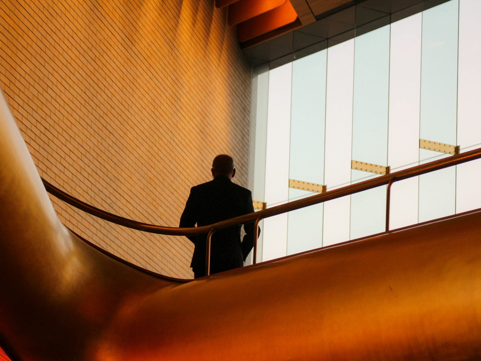 A man silhouetted on a curved staircase in an office atrium