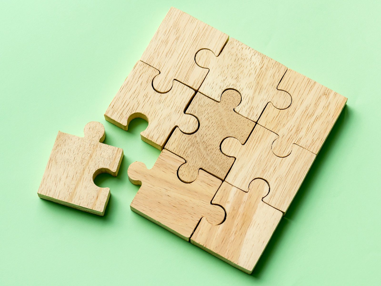 Wooden puzzle with one piece set apart from the rest