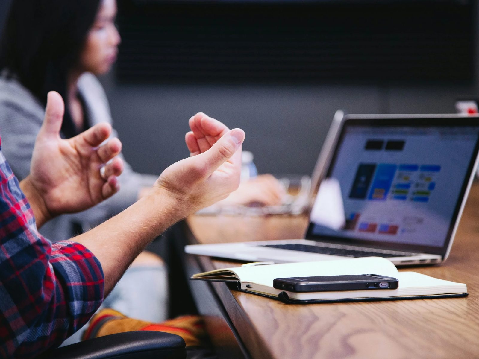 Hands gesturing next to a laptop during a discussion