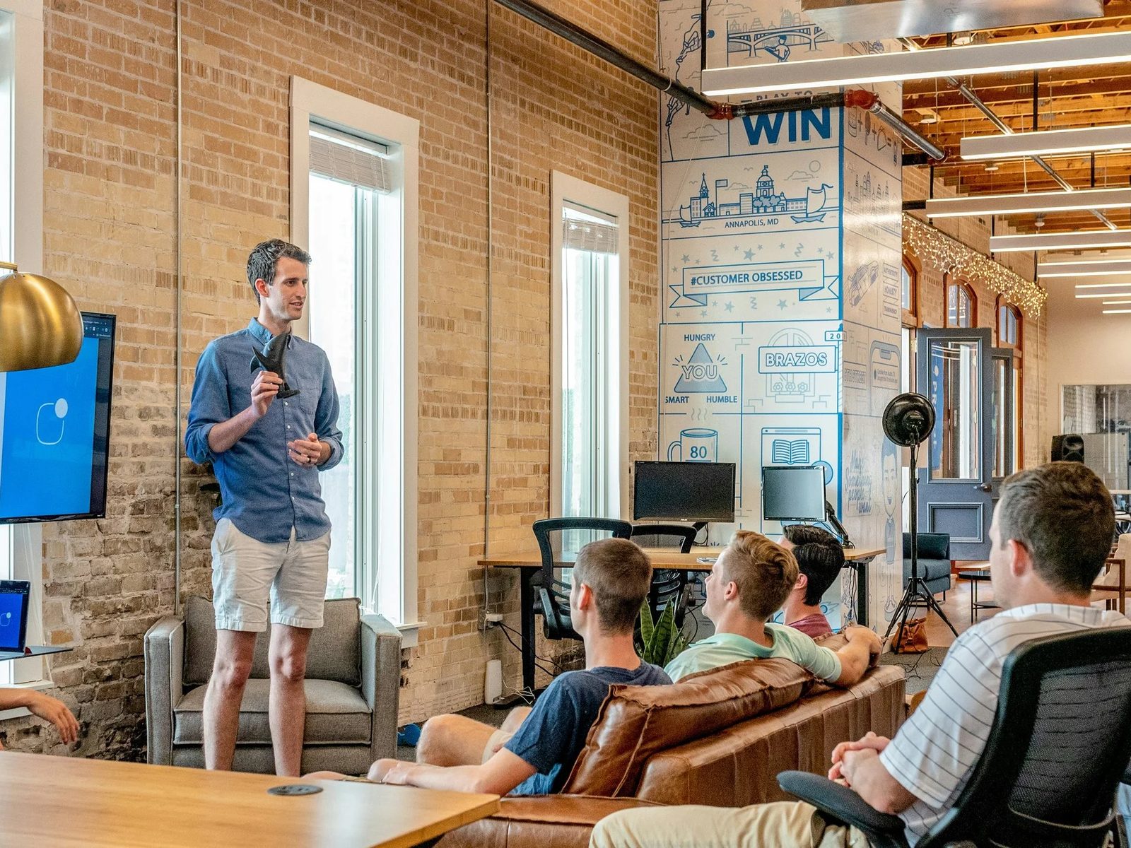 A man presenting to a team in a brick-walled office
