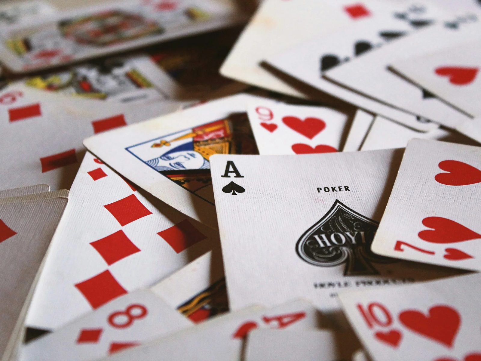 Playing cards scattered face up on a table, an ace of spades in the center