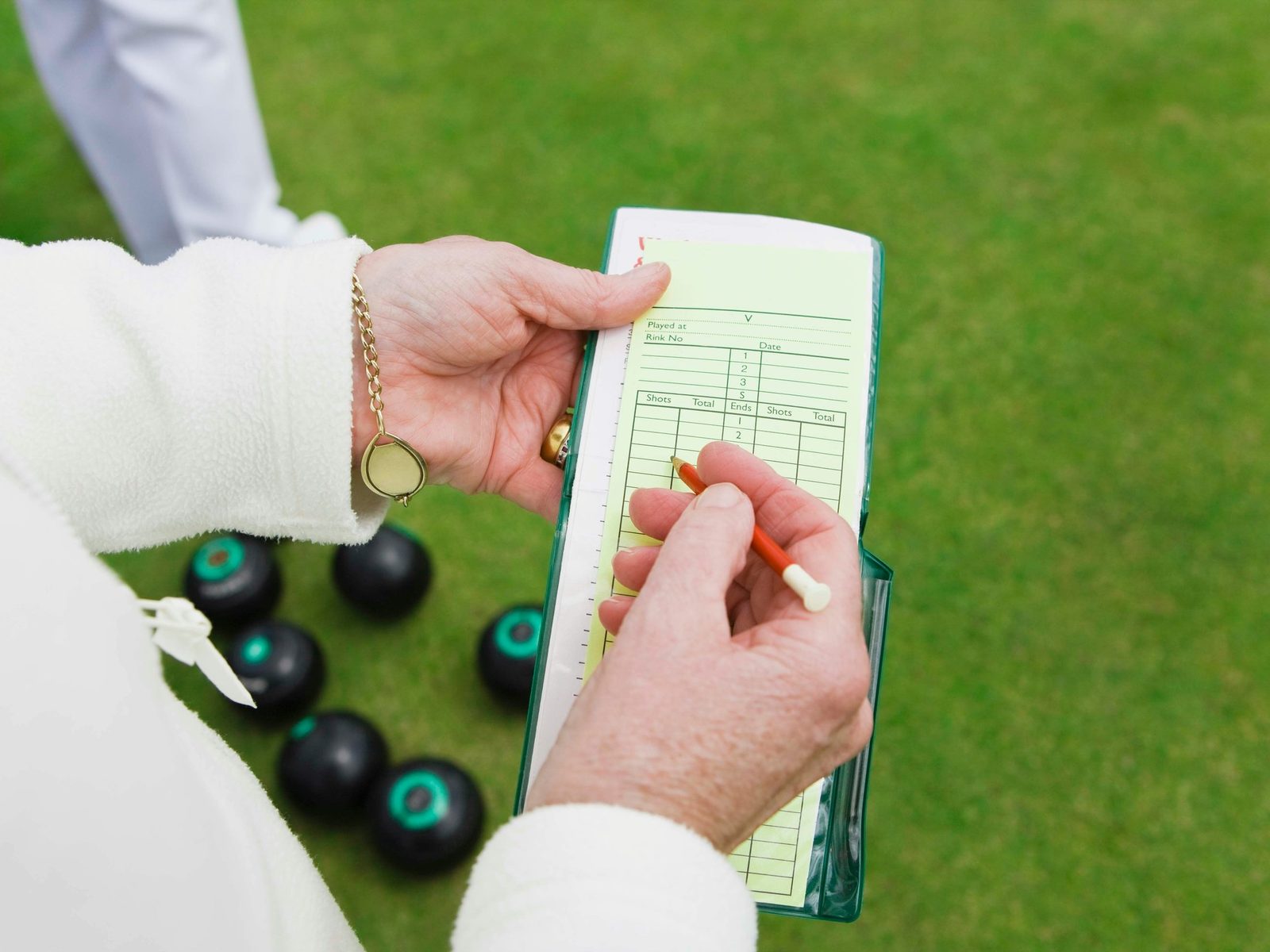 A lawn bowls player filling in a scorecard with a pencil